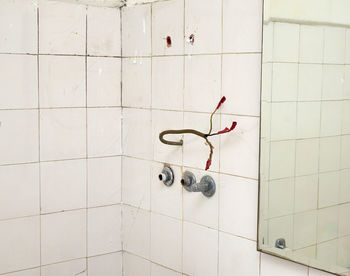 Bathroom with old white tiles and electric wires