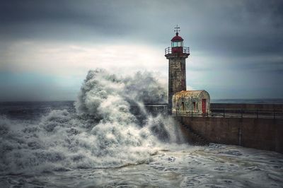 Lighthouse by sea against sky