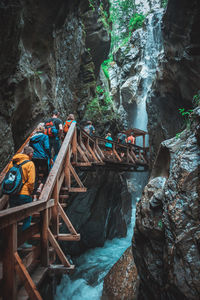 Group of people on rock against waterfall in forest