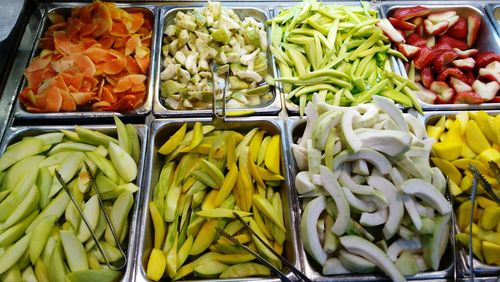 High angle view of fresh food in containers with serving tongs at restaurant