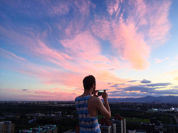 Man photographing against sky during sunset
