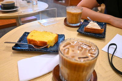 Close-up of coffee and cake served on table at a cozy cafe with friends