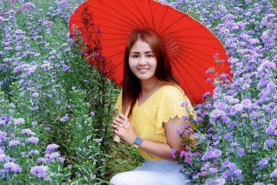 Portrait of smiling young woman against purple flowering plants