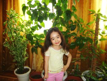 Portrait of smiling girl standing against plants at home