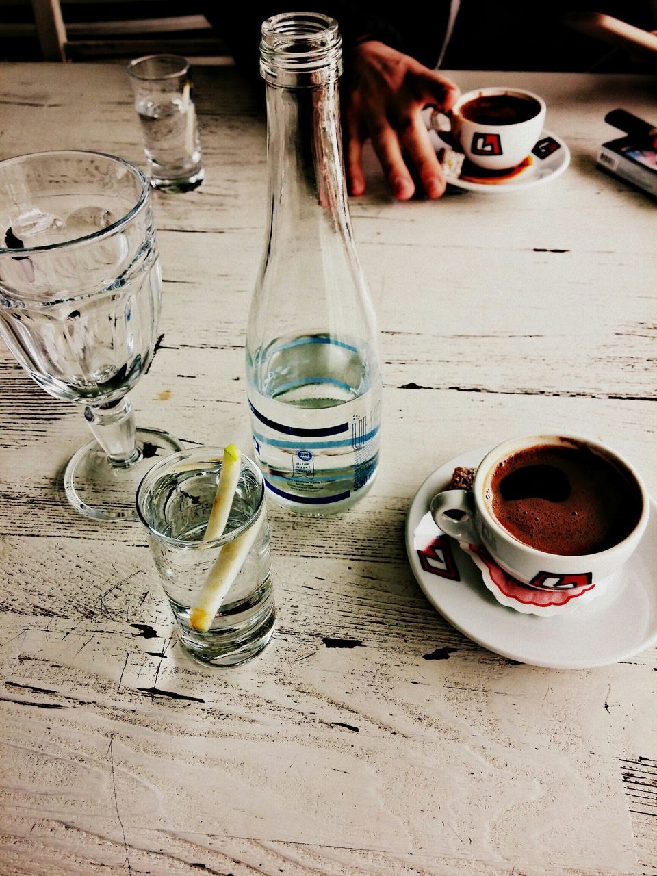 drink, refreshment, food and drink, table, drinking glass, still life, coffee cup, coffee - drink, bottle, alcohol, sunglasses, indoors, close-up, high angle view, wood - material, day, cup, sand, coffee, freshness