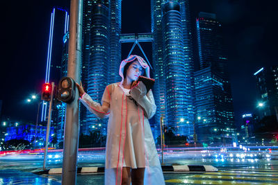 Woman using digital tablet against illuminated buildings in city at night