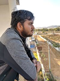 Side view of young man looking at camera