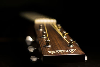 Close-up of guitar on table against black background