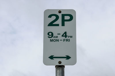 Low angle view of road parking sign against sky