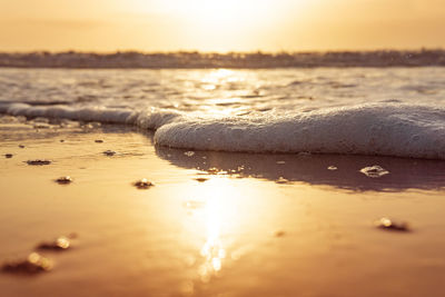 Surface level of beach against sky during sunset