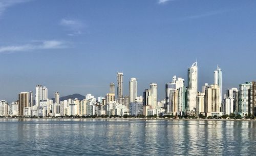 Sea by modern buildings against sky in city