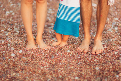 Low section of people standing on pebbles at beach