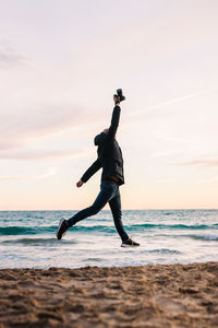 Full length of man at beach against sky during sunset