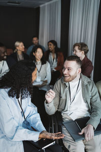 Happy male entrepreneur sitting on wheelchair and discussing with female entrepreneur during seminar at convention cente