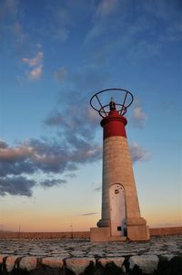 Lighthouse on beach against sky during sunset