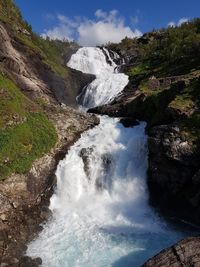 Scenic view of waterfall against sky