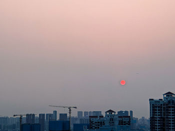 Buildings in city against clear sky at dusk