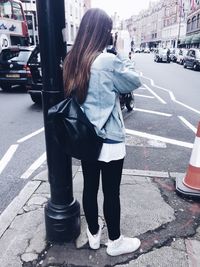 Rear view of woman standing on road in city