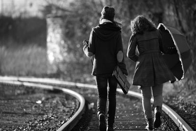 Rear view of friends walking on railroad tracks