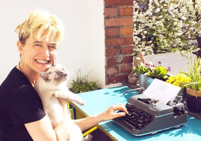 Portrait of young woman with cat using typewriter