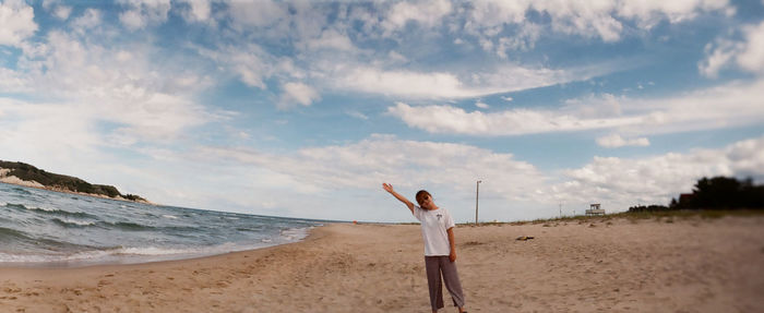 Panoramic view of woman standing at beach against sky