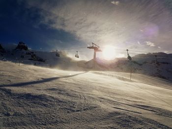 Snow covered landscape against sky during sunset