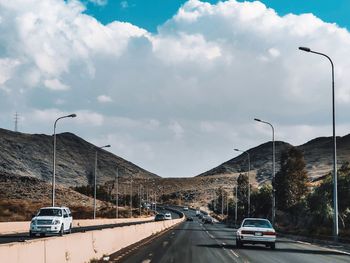 Cars on road against sky in city