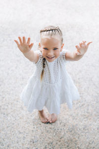 High angle portrait of smiling girl standing with arms raised