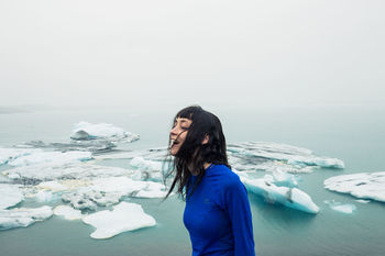 Side view of woman standing by sea during winter