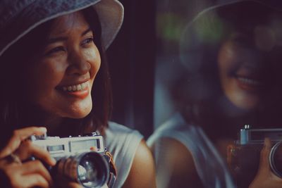 Smiling young woman looking away while holding camera