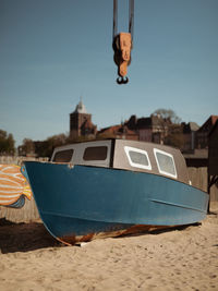 Boat moored on beach against clear blue sky