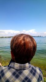 Rear view of man looking at sea against sky