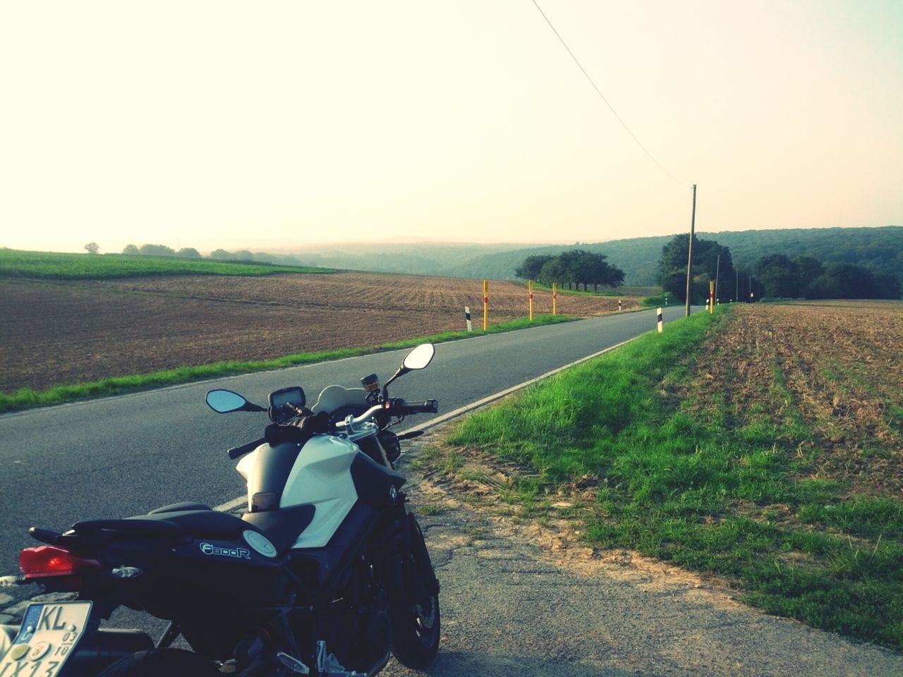 field, transportation, landscape, clear sky, grass, rural scene, agriculture, road, farm, land vehicle, grassy, tranquil scene, tranquility, mode of transport, the way forward, sky, nature, bicycle, country road, scenics