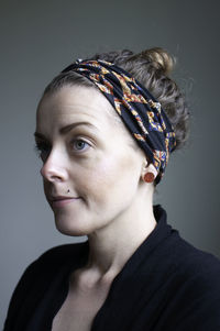 Close-up portrait of young woman against gray background