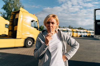 Portrait of young woman using mobile phone while standing on road