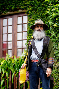 Portrait of man wearing hat standing against plants