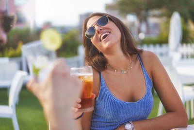 Couple having fun drinking fresh cocktails and beers outdoors wearing sunglasses