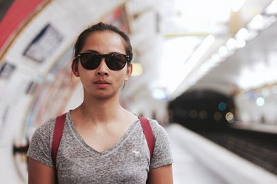 Portrait of young woman wearing sunglasses at subway station