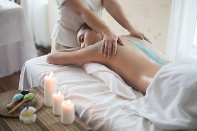 Midsection of therapist massaging young woman in spa