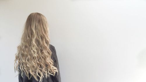 Rear view of woman with blond hair against white background