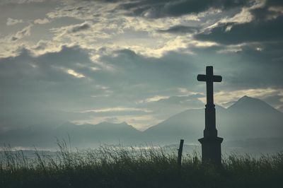 Cross on landscape against sky