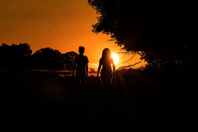 Silhouette people standing on field against sky during sunset