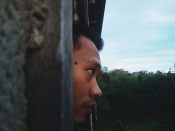 Portrait of teenage boy looking away against trees