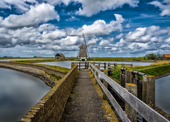 Scenic view of bridge and lake with windmill at distant