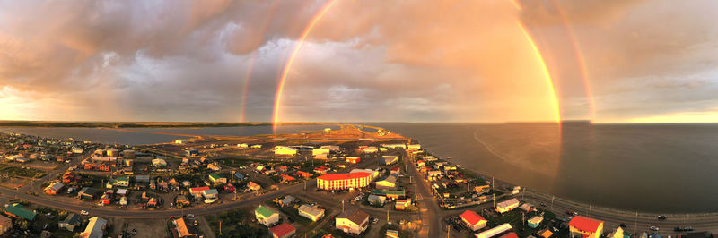 High angle view of rainbow over cityscape against sky during sunset