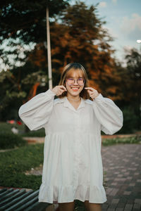 Portrait of young woman standing against trees