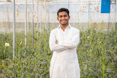 Portrait of a smiling young man standing in greenhouse