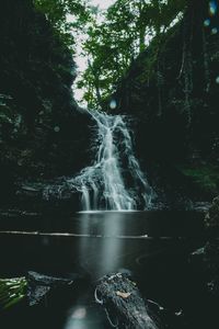Waterfall in forest against sky
