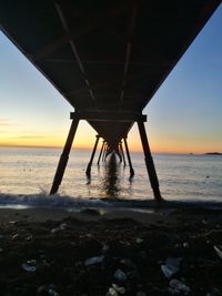 Silhouette pier on beach against sky during sunset