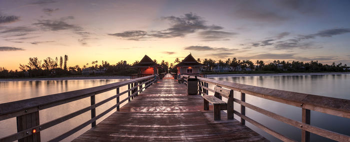 Pier over lake against sky during sunset